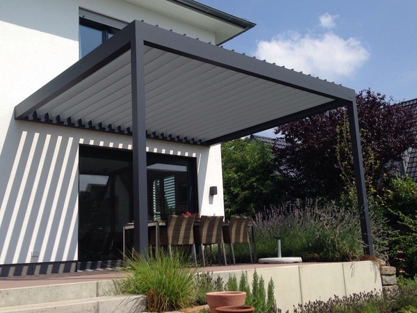 Moderne Terrassenüberdachung aus Aluminium am Einfamilienhaus mit Gartenmöbeln.