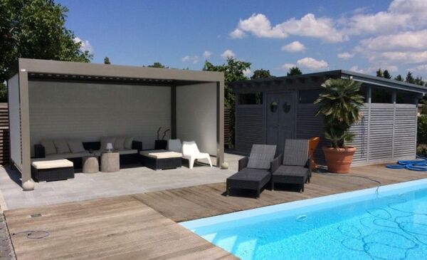 Moderne Terrasse mit Loungemöbeln, Pool, Gartenhaus und Palme im sonnigen Garten.
