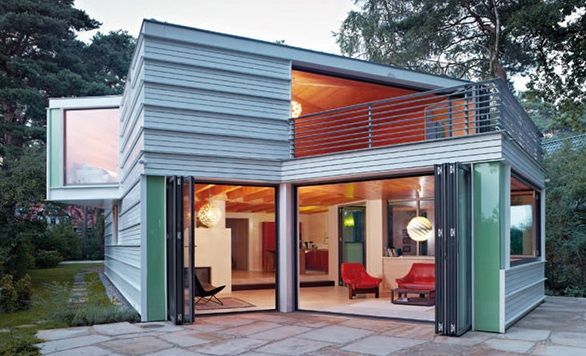 Modernes, zweistöckiges Containerhaus mit großen Glasfronten und offener Wohnfläche.