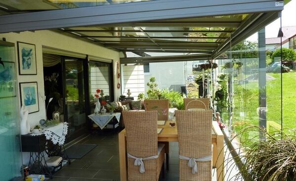 Moderner Wintergarten mit Glasüberdachung, Essbereich und Blick ins Grüne.