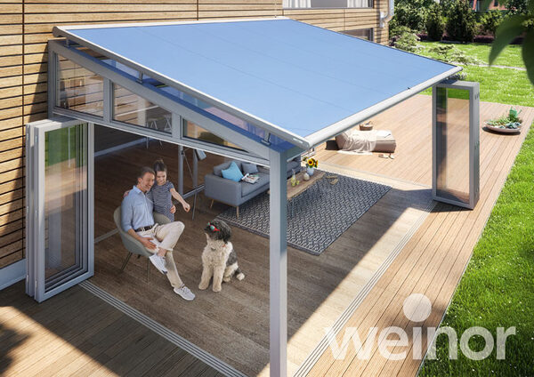 Moderne Terrassenüberdachung mit Glasdach, Familie und Hund auf Holzterrasse im Garten.
